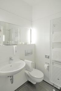a white bathroom with a toilet and a sink at Hotel Alt-Weimar in Weimar