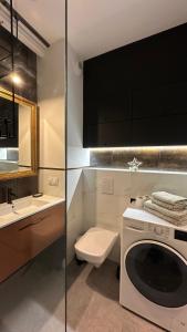 ein Badezimmer mit einer Waschmaschine und einem WC in der Unterkunft Apartament Linda in Białystok