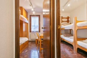 a room with bunk beds and a dining room with a table at Apartamento en SAPPORO in Vielha