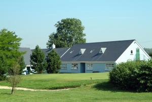 a white house with a black roof and a green yard at Richmond Park Golf Club in Watton