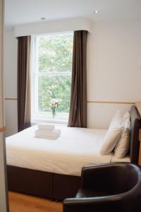 a bedroom with a bed with a window and a chair at Osborne Aparthotel in Eastbourne