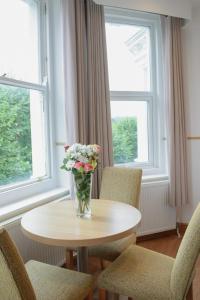 um vaso de flores sentado numa mesa em frente a uma janela em Osborne Aparthotel em Eastbourne