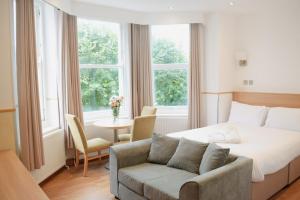 Osborne Aparthotel في إيستبورن: غرفة نوم بسرير واريكة وطاولة