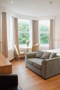 uma sala de estar com um sofá, uma mesa e janelas em Osborne Aparthotel em Eastbourne