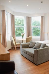 a living room with a couch and a table and windows at Osborne Aparthotel in Eastbourne