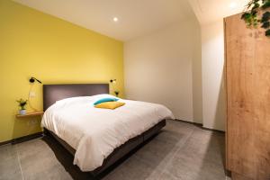 a bedroom with a bed and a yellow wall at SYBA Gastenverblijf in Evergem