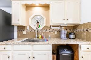 una cocina con armarios blancos y fregadero en SmartHome-Omaha Homestay Rooms en Omaha