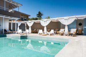 a swimming pool with a bunch of chairs next to a building at Anemos Suites by Estia in Karteros