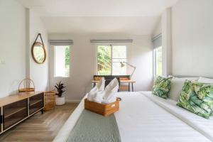 a white living room with a couch and a table at Naka Cozy House in Phuket City in Ban Rangeng