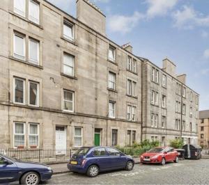 zwei Autos, die vor einem großen Gebäude geparkt sind in der Unterkunft Traveller Award Winner 2023 - Edinburgh Apartment with 3 Beds in Edinburgh