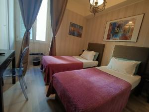 a hotel room with two beds and a desk at Hotel Villa La Tour in Nice