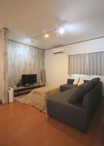 sala de estar con sofá y TV de pantalla plana en たび宿SeKKoku en Takagi