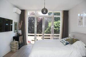 een slaapkamer met een wit bed en een groot raam bij Spacious apartment with garden in Amsterdam