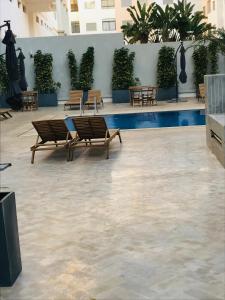 un patio con bancos y una piscina en un edificio en Apparemment avec piscine, en Kenitra