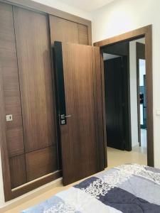1 dormitorio con puertas de madera y 1 cama en Apparemment avec piscine en Kenitra