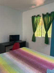 um quarto com uma cama de arco-íris, uma secretária e uma janela em Casa São bento 193 em Olinda