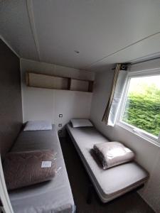 una piccola camera con due letti e una finestra di Mobil home équipé camping 5* a Houlgate