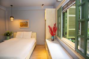sypialnia z łóżkiem i oknem z zielonymi okiennicami w obiekcie Chez Van w mieście Hanoi