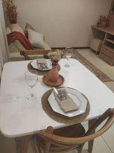 a white table with two plates and glasses on it at Apartamento Aconchegante in Brasília