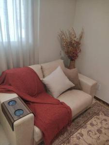 a couch with a blanket and a remote control on it at Apartamento Aconchegante in Brasília