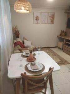 - une table à manger avec 2 chaises et une table blanche avec des verres à vin dans l'établissement Apartamento Aconchegante, à Brasilia