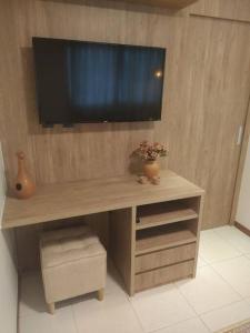 a wooden desk with a television on a wall at Apartamento Aconchegante in Brasília