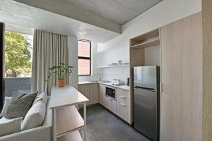 a small kitchen with a couch and a refrigerator at One26 On M Luxury serviced apartments - By Elevate in Cape Town