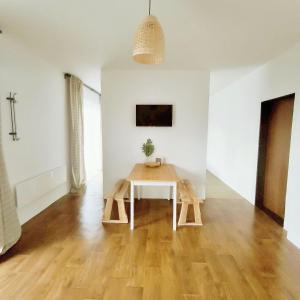 Cette chambre blanche dispose d'une table en bois. dans l'établissement GuestHouse Maison Standard, à Kula