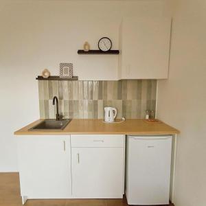 een keuken met een wastafel en een klok aan de muur bij GuestHouse Maison Standard in Kula
