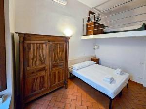um pequeno quarto com uma cama e um armário de madeira em Confortevole App Centro Storico em Florença