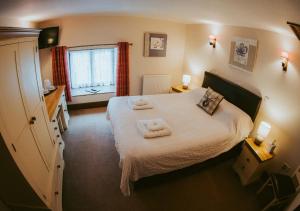 1 dormitorio con 1 cama con toallas en The Heathfield Inn, en Honiton