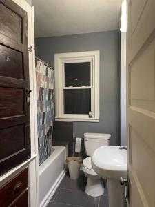 La salle de bains est pourvue de toilettes, d'un lavabo et d'une fenêtre. dans l'établissement Belle Isle Cottage - 1905 Historic Home near city, à Detroit