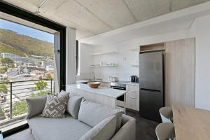 a living room with a couch and a kitchen at One26 On M Luxury serviced apartments - By Elevate in Cape Town