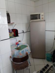 a kitchen with a table and a microwave on top of a refrigerator at Quarto Vila Mariana in São Paulo