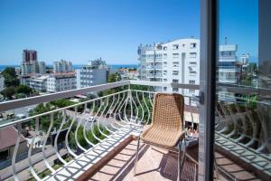 a chair on a balcony with a view of a city at Lara Dinc Hotel in Antalya