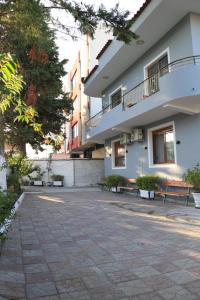 a building with benches in front of a building at Albora Guest House in Fier