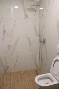 a white bathroom with a toilet and a shower at Albora Guest House in Fier