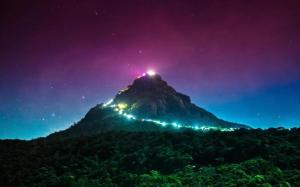 a mountain with lights on top of it at night at Subash Hotel in Adams Peak