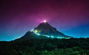 a mountain with lights on top of it at night at Subash Hotel in Nallathanniya