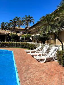 a group of lounge chairs next to a swimming pool at Fênix Plaza Hotel in Aquidauana