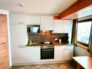 una cocina con armarios blancos y fregadero en Apartments Pitztaler Nachtigall, en Arzl im Pitztal