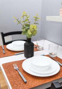 une table avec des assiettes blanches et un vase avec des fleurs dans l'établissement MIAMI APPARTEMENT, à Lyon