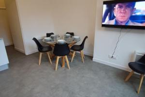 a room with a table with chairs and a flat screen tv at TOK TOK S2 - Appartement 1Ch Plein cœur de Seclin in Seclin