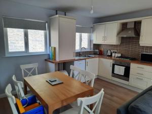 a kitchen and dining room with a wooden table at Cushendall Cottage, Moneyvart in Cushendall