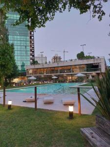 a swimming pool with benches and umbrellas in front of a building at GALA Dptos. Temp. Condominios del Alto in Rosario