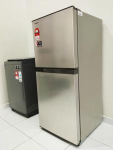 a stainless steel refrigerator next to a trash can at Mukmin 2 Stay in Melaka