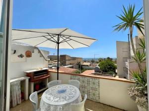 eine Terrasse mit einem Tisch und einem Sonnenschirm auf dem Balkon in der Unterkunft Le Muse casa vacanze in Scoglitti