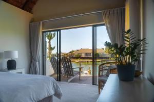 a bedroom with a bed and a view of a balcony at CANAL GUEST HOUSE - Waterfront Boutique B&B in St Francis Bay +50 photos