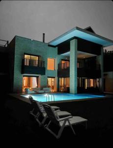 una casa con due sedie di fronte a una piscina di Villa Mazagan de luxe 6 chambres face mer 1000m2 a El Jadida
