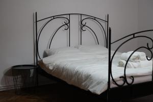 Cama de metal negro con sábanas y almohadas blancas en FeriAna Residence, en Miercurea-Ciuc